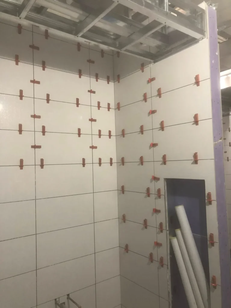 Large format stacked white ceramic shower wall tile installation using precision leveling clips by DMtilellc in Westport CT