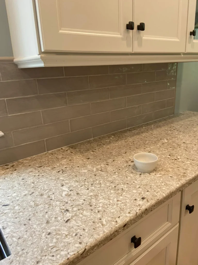 Gloss taupe subway tile kitchen backsplash installation beneath white cabinets and granite countertops by DMtilellc in West Hartford CT