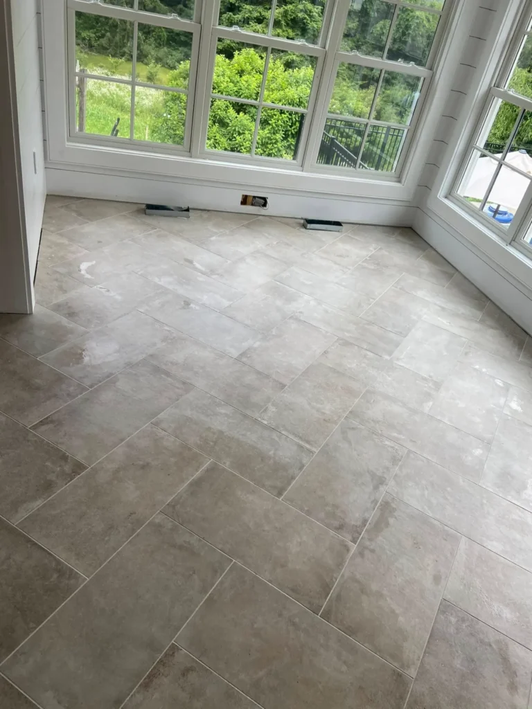 Ivory travertine look porcelain floor tiles installed in a herringbone pattern inside a sunroom by DMtilellc in Greenwich CT